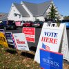 A Vote Here sign is posted amongst political signs as people arrive to vote at the Rutherford County Annex Building, an early voting site, Oct. 17, 2024, in Rutherfordton, N.C.