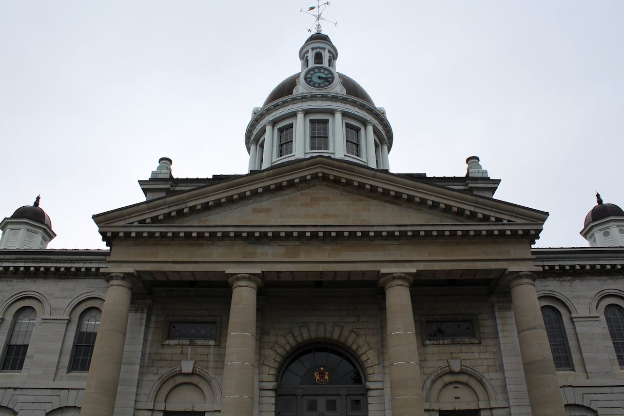 An large, domed building made of grey limestone with a clock at the top.