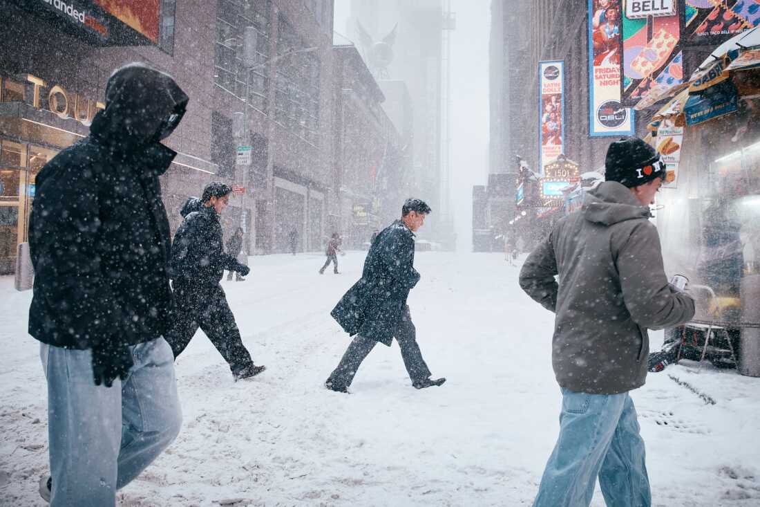 People cross the street in Times Square during a snowstorm on Jan. 25, 2026 in New York City.