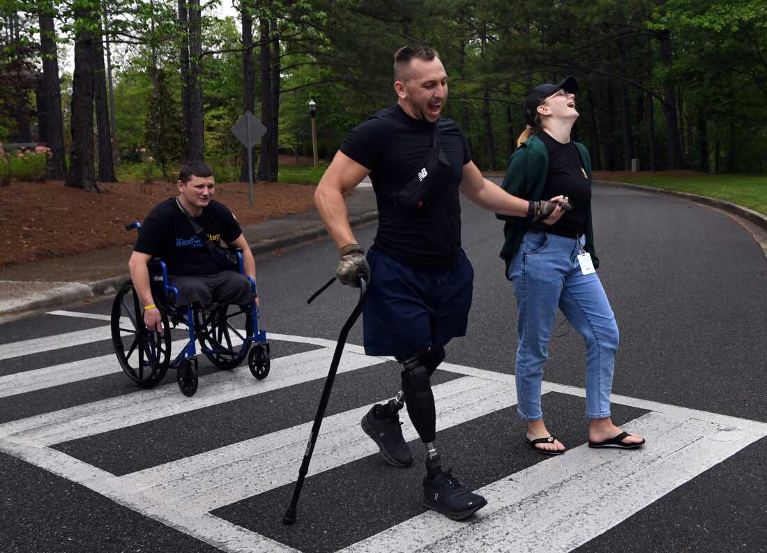 Sgt. Misha Varvarych, a Ukrainian war amputee holds hands with his fiancé Ira Botvynska as he walks on his new prosthetic legs