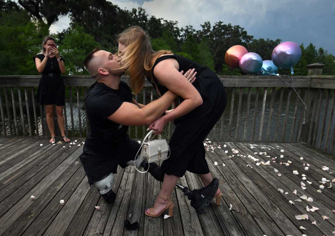 On bended prosthetic knee, Sgt. Misha Varvarych, a Ukrainian amputee and his fiancé Ira Botvynska kiss after he proposed to her in Orlando FL