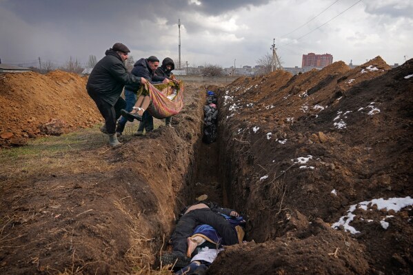 Bodies are placed into a mass grave on the outskirts of Mariupol, Ukraine, Wednesday, March 9, 2022. (AP Photo/Evgeniy Maloletka, File)