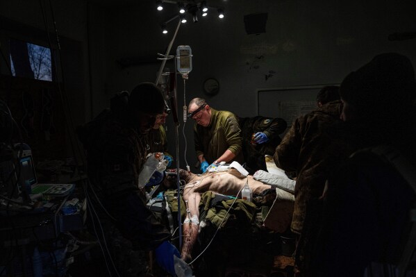 Ukrainian military doctors treat an injured comrade who was evacuated from the battlefield in a hospital in the Donetsk region, Ukraine, Monday, Jan. 9, 2023. The serviceman did not survive. (AP Photo/Evgeniy Maloletka, File)