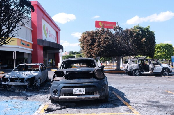 Charred vehicles sit in a parking lot sit outside a shopping mall in Guadalajara, Jalisco state, Mexico, Sunday, Feb. 22, 2026, as authorities reported the Mexican Army killed Jalisco New Generation Cartel leader Nemesio Oseguera, known as "El Mencho. (AP Photo/Alejandra Leyva)