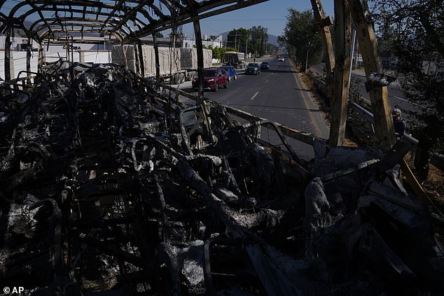 Vehicles drive past a charred bus the day after the Mexican army killed Jalisco New Generation Cartel leader Nemesio Oseguera, known as "El Mencho," in Guadalajara, Mexico, Monday, Feb. 23, 2026. (AP Photo/Marco Ugarte)