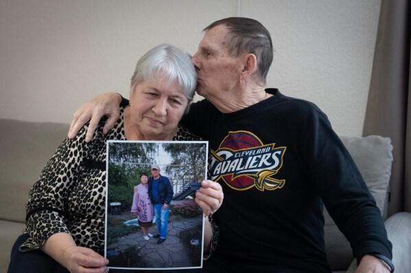 Liudmyla Shytik, 77, is kissed by her husband Viktor, 78, while holding a photograph of themselves outside their home, which was destroyed in Russia's full-scale invasion, at their social housing apartment in the Kyiv region of Ukraine, Wednesday, Feb. 18, 2026. (AP Photo/Efrem Lukatsky)