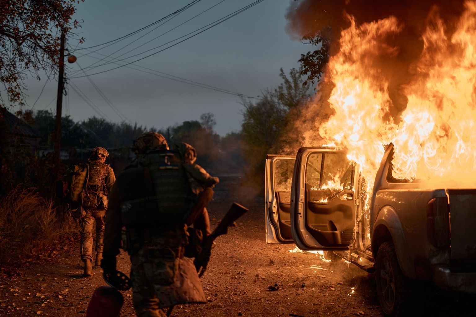 Ukrainian soldiers walk past a vehicle recently struck by a Russian FPV drone near the front line in Kostiantynivka, Donetsk Oblast, Ukraine, on Oct. 16, 2025. 