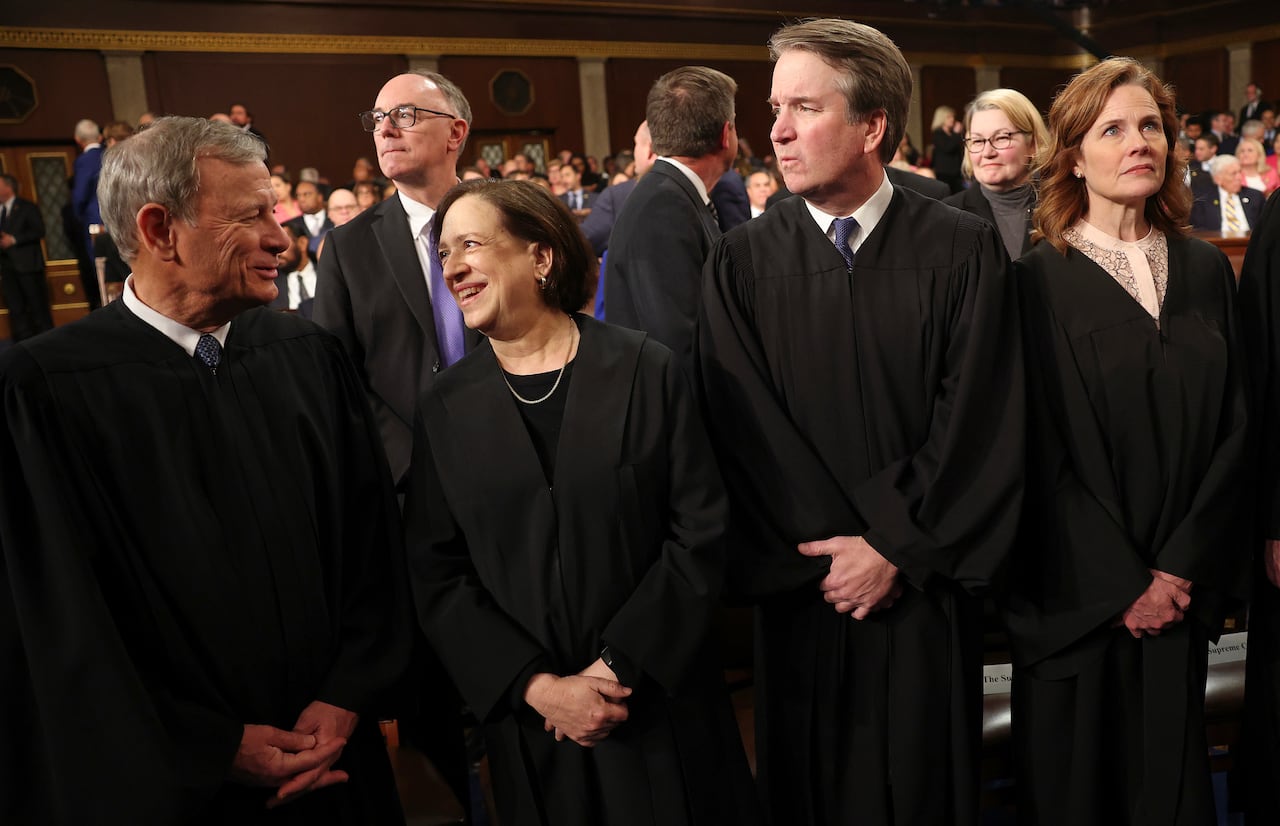 John Roberts, Elena Kagan, Brett Kavanaugh and Amy Coney Barrett, all stand wearing black judicial robes.  
