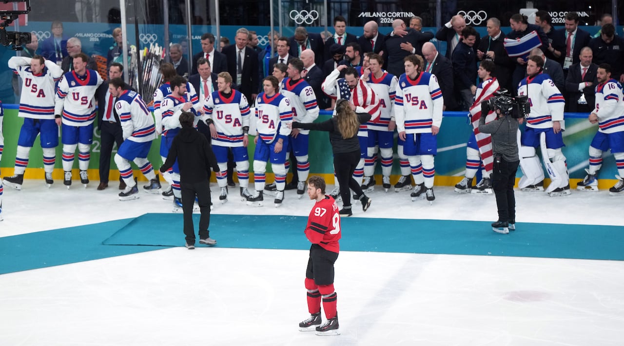 Canada's Connor McDavid skates alone past many celebrating Team USA players. 