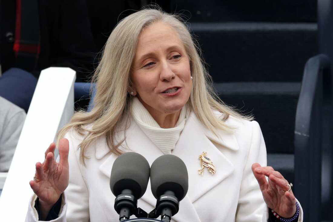Virginia Governor Abigail Spanberger stands at a pair of microphones.