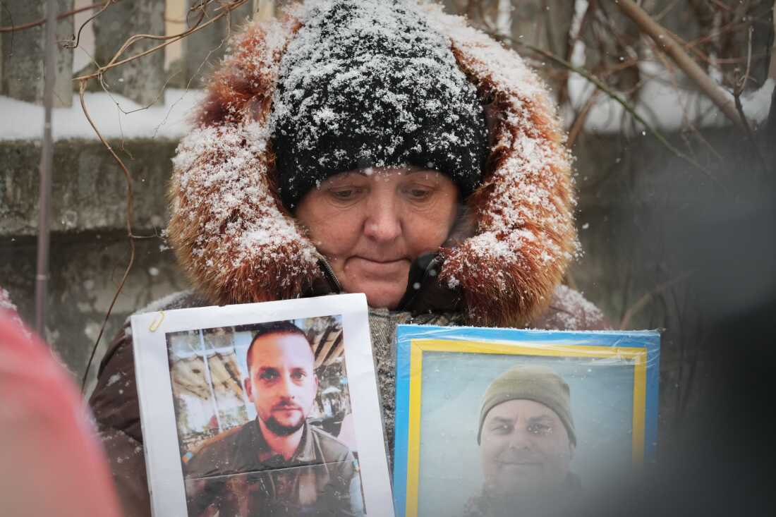 A woman holds photos of her missing relatives as Ukrainian soldiers return from captivity during a prisoner exchange between Russia and Ukraine in Ukraine's Chernihiv region on February 5.