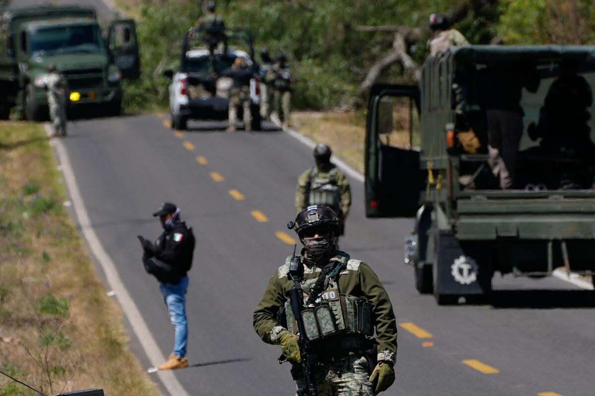 Troops in uniform near vehicles on a road