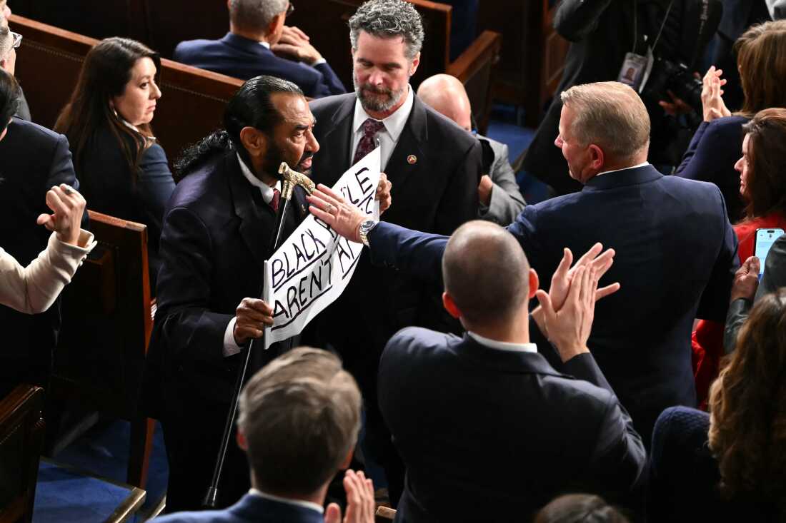 U.S. Rep. Al Green exits  the House Chamber as he holds a sign reading "Black people aren't apes."