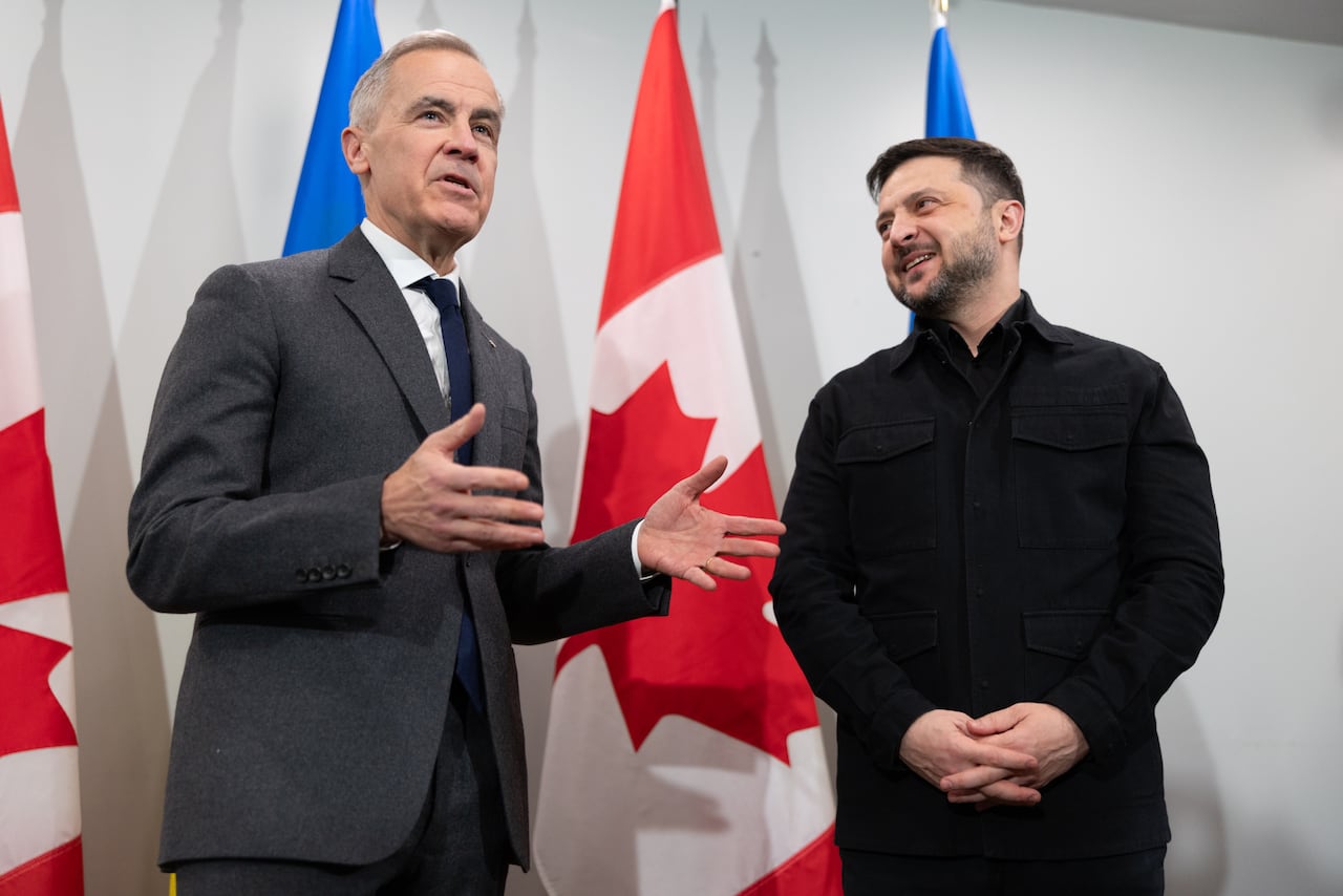 Two men standing and talking in front of Canadian and Ukrainian flags
