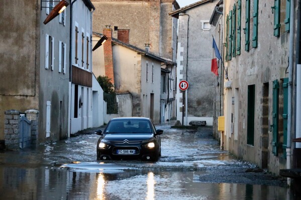 A car drives through a flooded street of Saint-Germain de Confolens as severe flooding hits western France amid storm Nils, Thursday, Feb. 12, 2026. (AP Photo/Yohan Bonnet)