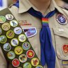 FILE - Merit badges and a rainbow-colored neckerchief slider are affixed on a Boy Scout uniform. The U.S. organization, which now welcomes girls into the program and allows them to work toward the coveted Eagle Scout rank, announced May 7, 2024, that it would change its name to Scouting America as it focuses on inclusion.