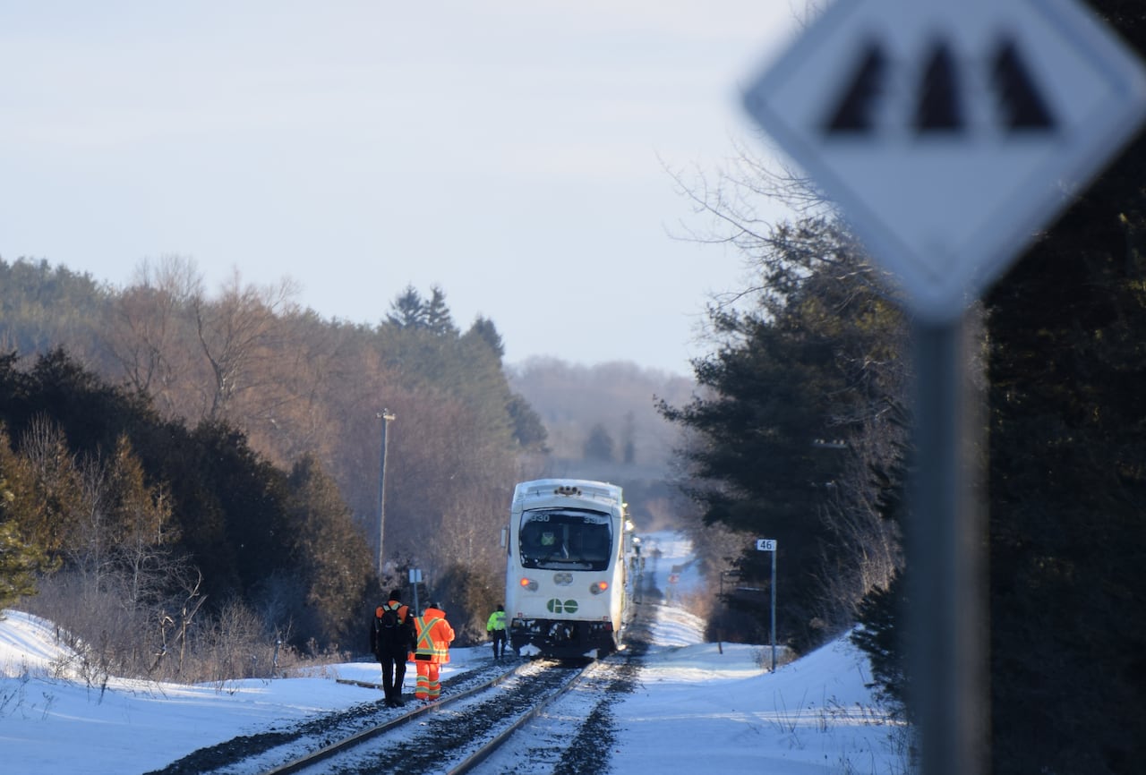 people wearing orange hazard clothing on train tracks.