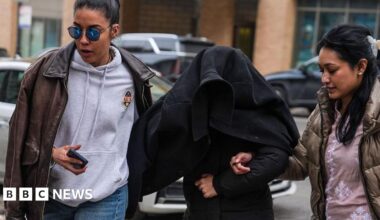 Elmina Aghayeva seen under a jacket being led away by agents