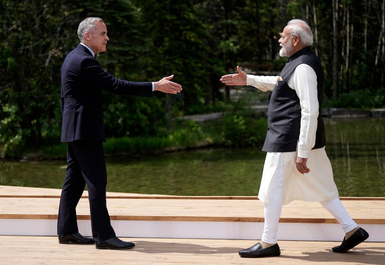 Prime Minister Mark Carney and India's Prime Minister Narendra Modi reach to shake hands at the G7 Summit in Kananaskis, Alta.