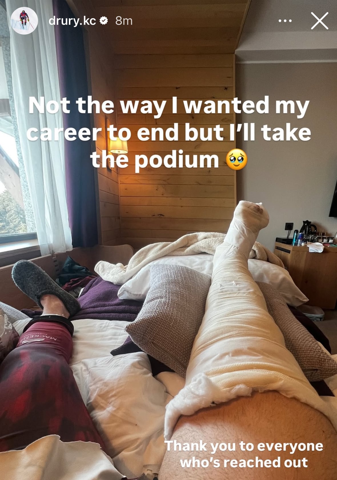 A man's legs are shown on a bed, with one wrapped in gauze. The text 'Not the way I wanted my career to end but I'll take the podium' and an emoji is shown.