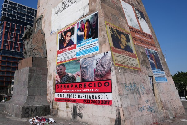 Posters bearing the faces of missing people cover the Ninos Heroes monument in Guadalajara, Mexico, Wednesday, Feb. 25, 2026. (AP Photo/Marco Ugarte)