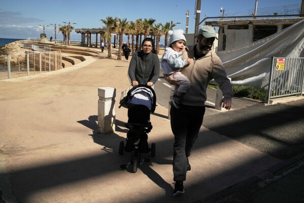 A couple with their two children rush to a shelter after a warning siren sounds following Israeli strikes in Iran, in Haifa, northern Israel, Saturday, Feb. 28, 2026. (AP Photo/Leo Correa)