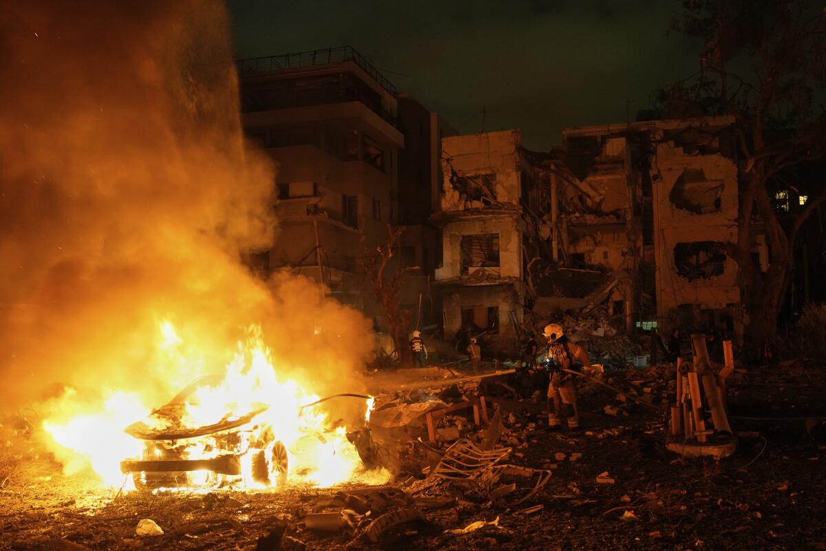 Firefighters work to extinguish a blaze near destroyed buildings 