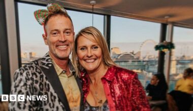 A middle-aged couple are in fancy dress at a party. They look happy.