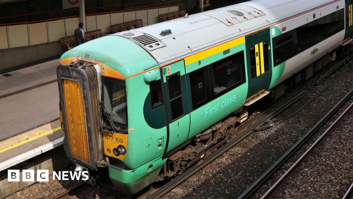 An elevated side view of a green and yellow Govia Thameslink train sitting at a platform.