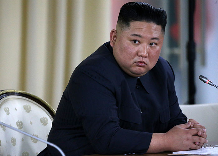 North Korean leader wearing black suit, seated at conference table, symbolizing strict control over citizens and media.