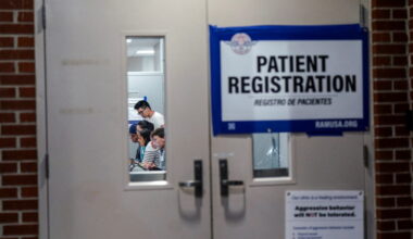Staff and volunteers are seen through a door as they check in patients at a pop-up Remote Area Medical (RAM) health clinic...