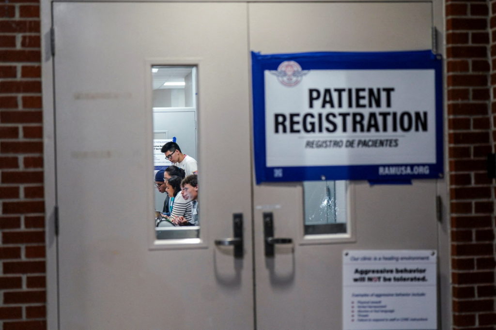 Staff and volunteers are seen through a door as they check in patients at a pop-up Remote Area Medical (RAM) health clinic...