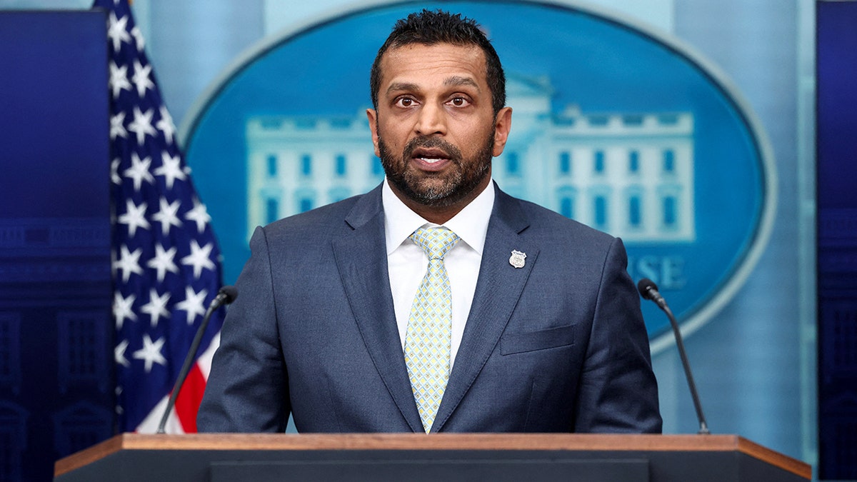 FBI Director Kash Patel speaks at a White House briefing podium with the U.S. flag behind him.