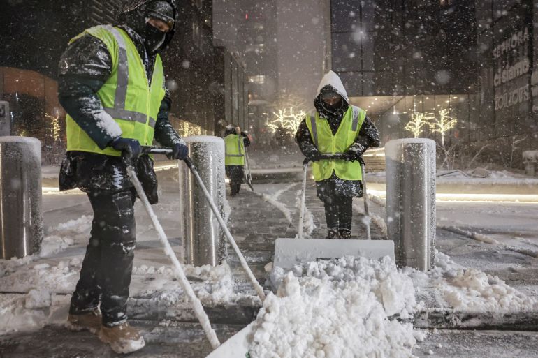 Workers clear snow from a street 