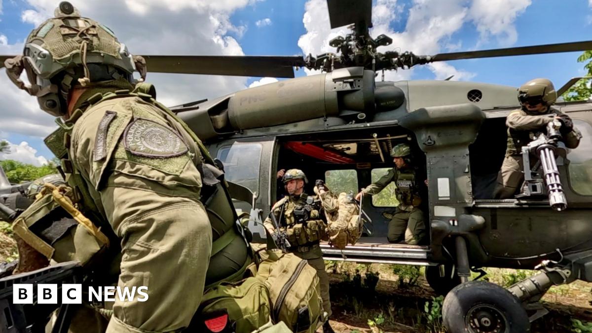 Commandos land on a cocoa farm in Colombia. They are wearing military-looking uniforms with helmets, and disembarking from a helicopter.
