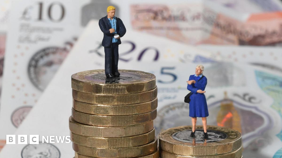 Tiny models of a man and woman on a pile of coins and bank notes. The male models are on the higher pile, visualising the gender pay gap.