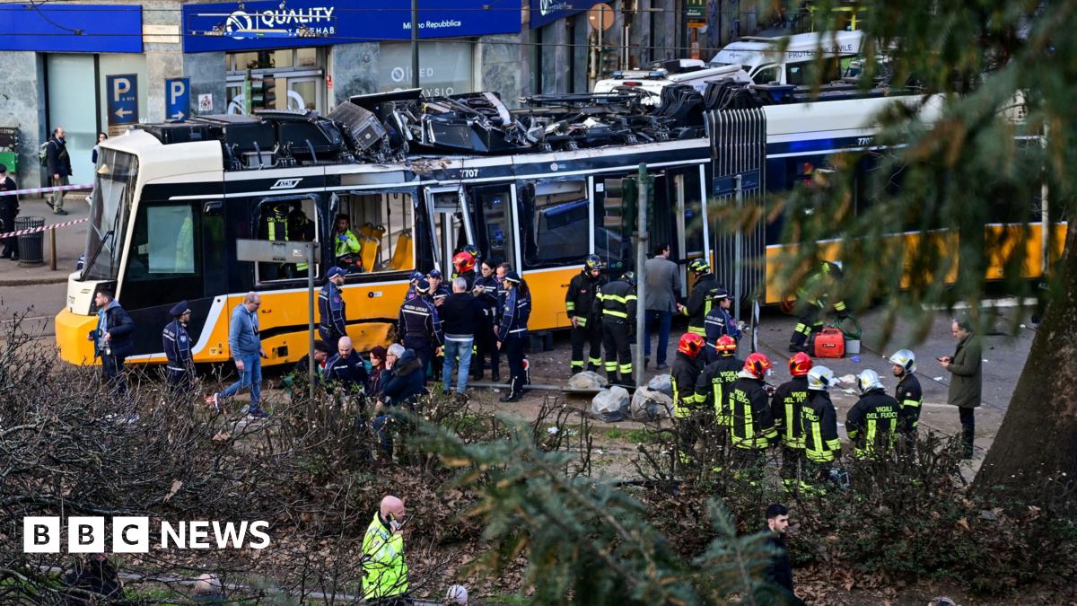 Emergency workers stand near damaged tram at scene of crash