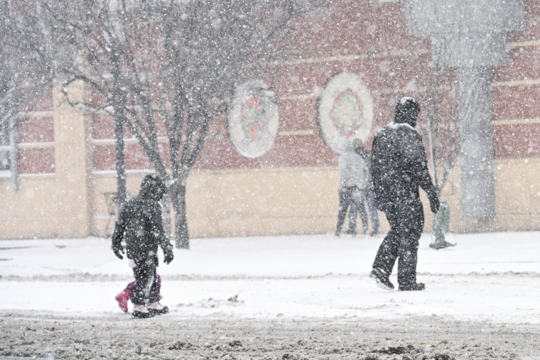Two people walk in the snow outside