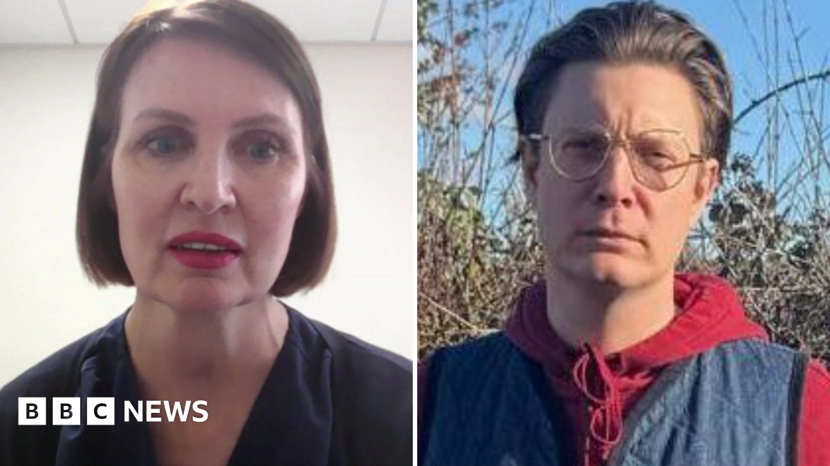A large office building with the name “PM House” displayed prominently on its exterior. The building has a modern, rectangular design with multiple rows of windows and light grey cladding. In the foreground, a tall sign also reads “PM House” in blue lettering on a white background, framed by a dark blue border. Several cars are parked in front of the building, suggesting a business or office complex.