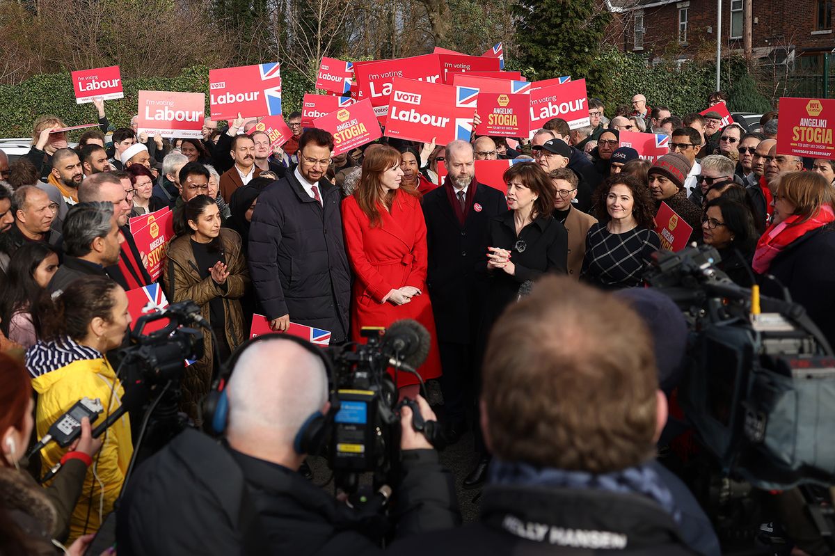 Angeliki Stogia stands in between a crowd of Labour supporters and a row of TV cameras and microphones