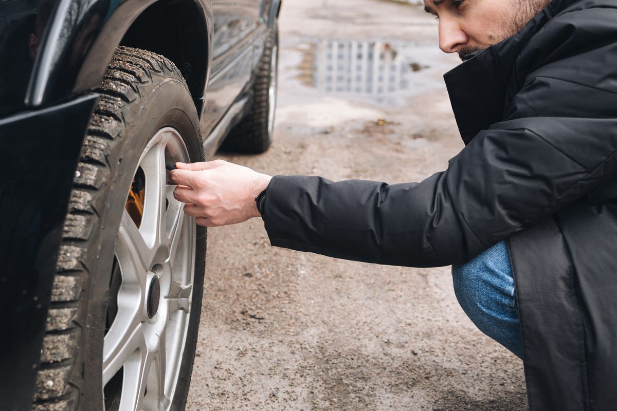 Man checking status of his car's tires. Male checking car tire pressure