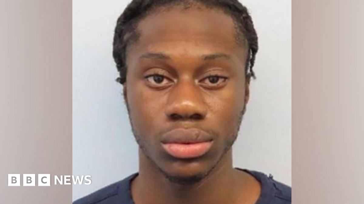 Custody photograph of a Daniel Boakye with braided hair wearing a dark T-shirt, facing the camera against a plain light grey background.