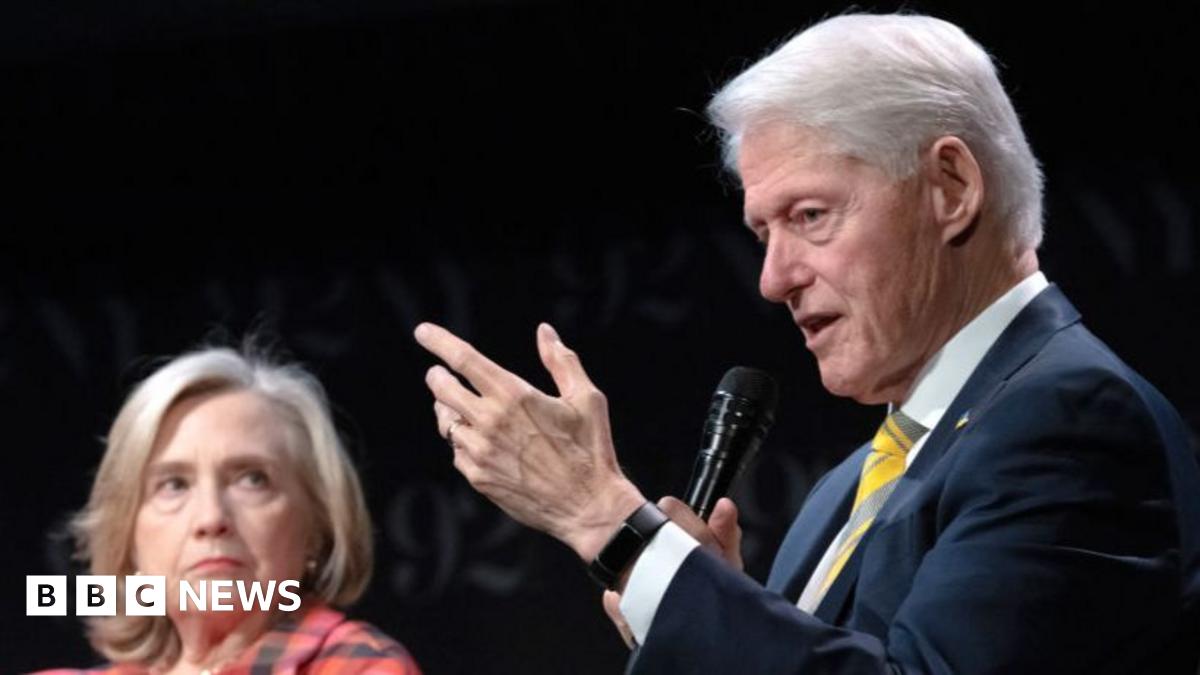 Former President Bill Clinton lays in a hot tub. Sitting next to him is a person whose face has been redacted