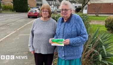 Two elderly women. They are outside their house.
