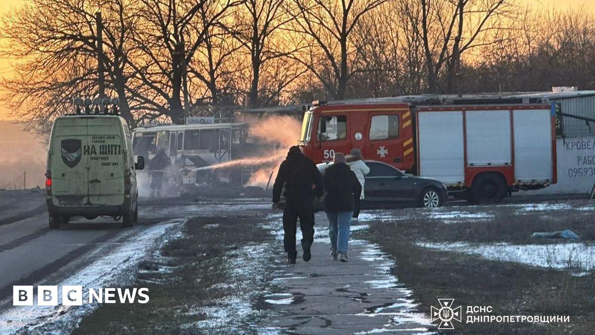 A bus at twilight beside a fire engine