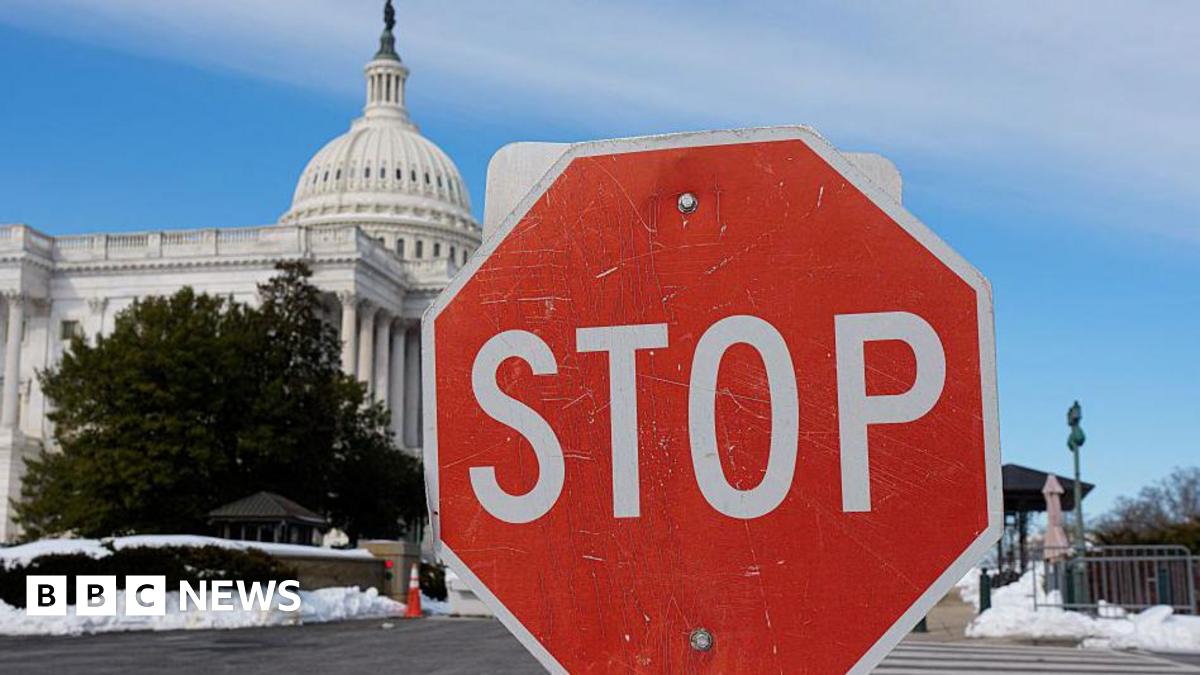 A stop sign is visible amid patches of snow in front of the US Capitol Building in Washington, DC