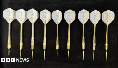 A man sharpening a golden dart in a workshop.