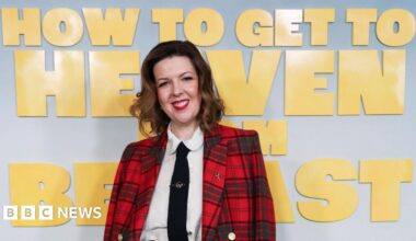 Six woman stand and look to the camera. They stand in front of a promo board which has the title 'How to get to heaven from Belfast' on it in yellow font.