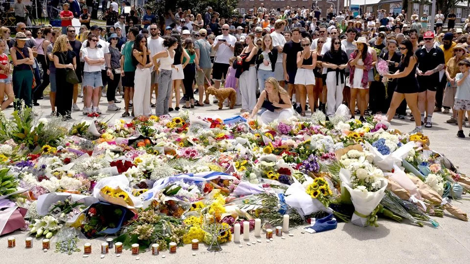 Mourners gather by floral tributes at the Bondi Pavillion in memory of the victims of the shooting at Bondi Beach, in Sydney on December 15, 2025. - Saeed Khan/AFP/Getty Images