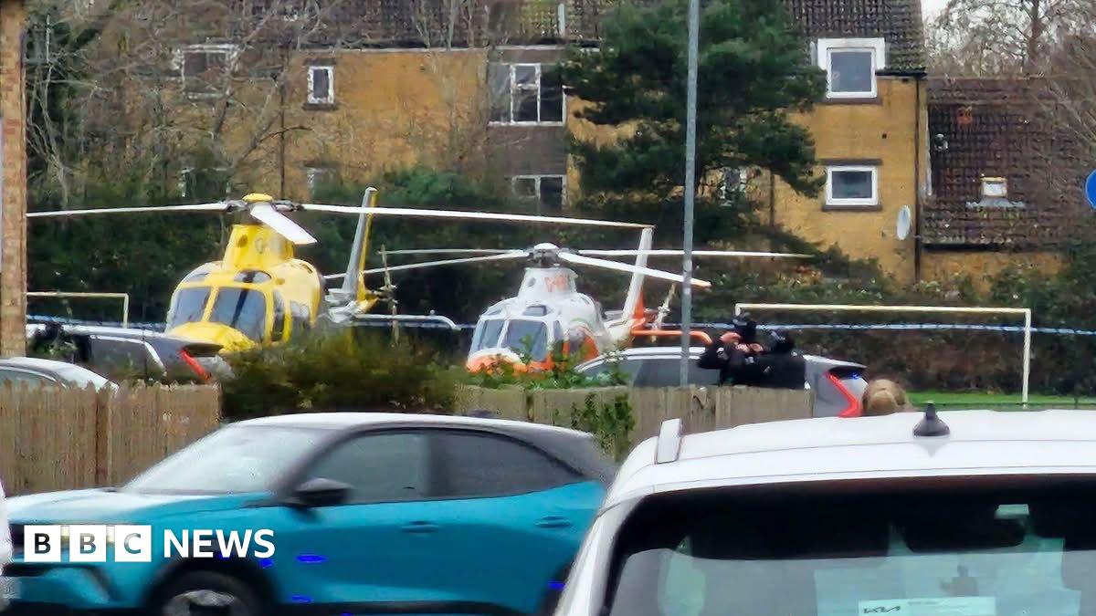 Two helicopters on the ground in an urban park.